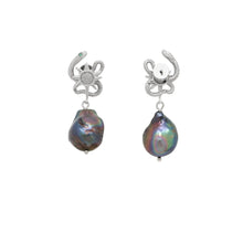 Pair of earrings with serpent design and black pearl on a white background