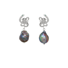 Pair of earrings with serpent design and black pearl on a white background