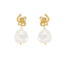 Gold serpent earrings with pearl drops on a white background