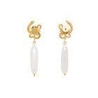 Gold serpent shaped earrings with a pearl on a light beige background
