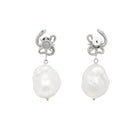 Pair of pearl earrings with silver snake charms on a white background