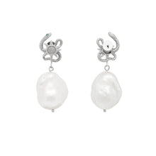 Pair of pearl earrings with silver snake charms on a white background
