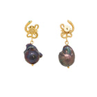 Pair of earrings with gold crab-like charms and dark pearls on a white background